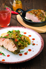 Closeup view of oven-baked meat with braised cabbage and zucchini and hot spicy sauce