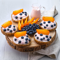 Sweet buns with soft cheese, blueberry and slice of persimmon on white wooden table