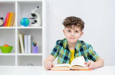 Portrait of a smart boy with  a book at home