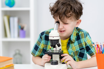 Young student looks through microscope at home