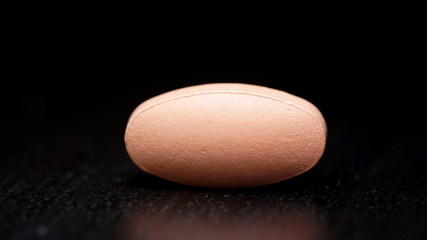 the oval tablet is isolated on a black background.