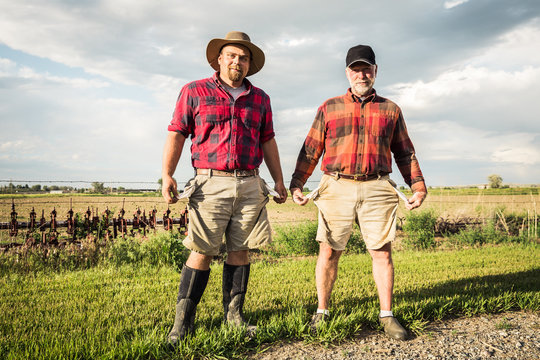 Portrait of farmers pulling out empty pockets after long day of work, father and son. Laurel, Montana, USA