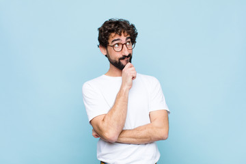 young bearded man with glasses against blue wall