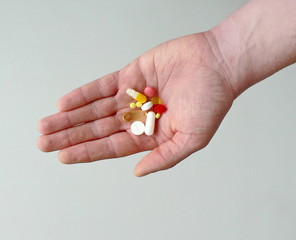 Colorful capsules and pills holds in hand a man. Influenza epidemic concept, vitamins for beauty, drug addiction treatment, healthcare, pharmacy. Treatment of diseases with medicines. Copy space. 