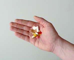 Colorful capsules and pills holds in hand a man. Influenza epidemic concept, vitamins for beauty, drug addiction treatment, healthcare, pharmacy. Treatment of diseases with medicines. Copy space. 