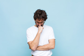 young bearded man with glasses against blue wall