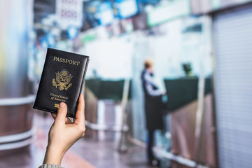 Woman hand holding american passport with boarding pass in the airport opposite Immigration and passport control. concept. America. USA
