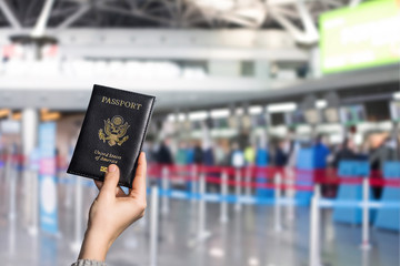 Obraz premium Woman hand holding american passport in the airport opposite check-in area. concept. America. USA
