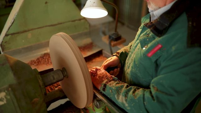 Craftsman working on woodworking lathe machine in the carpenter workshop. Woodworker handles product by lathe and graver