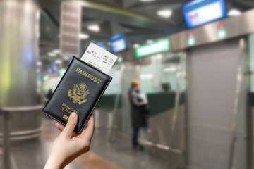 Woman hand holding american passport with boarding pass in the airport opposite Immigration and...