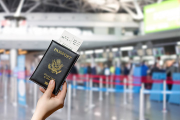 Woman hand holding american passport with boarding pass in the airport opposite check-in area. concept. America. USA