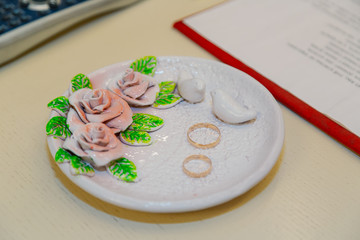 Gold wedding rings on a decorated plate.