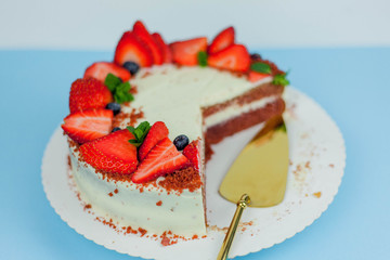 Beautiful cake with berries with butter cream on a blue background. Cake with red cakes.