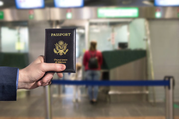 Man (businessman)  in a blue suit holding american passport in the airport opposite Immigration and passport control. concept. America. USA