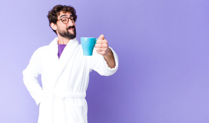 young crazy bearded man  wearing bathrobe and having a coffee