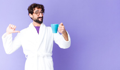 young crazy bearded man  wearing bathrobe and having a coffee