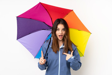 Woman holding an umbrella isolated on white background with surprise facial expression