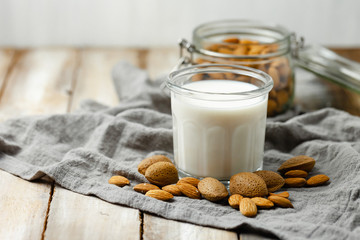 Fresh organic vegan almond milk. Alternative source of protein for vegetarians. Raw almonds as ingredients, peeled and unpeeled. Concept of healthy lifestyle. Closeup, wooden background, copy space