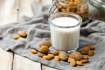 Fresh organic vegan almond milk. Alternative source of protein for vegetarians. Raw almonds as ingredients, peeled and unpeeled. Concept of healthy lifestyle. Closeup, wooden background