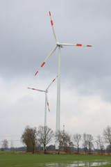 Fototapeta premium Windräder auf zwischen Feldern produzieren für die Energiewende Ökostrom