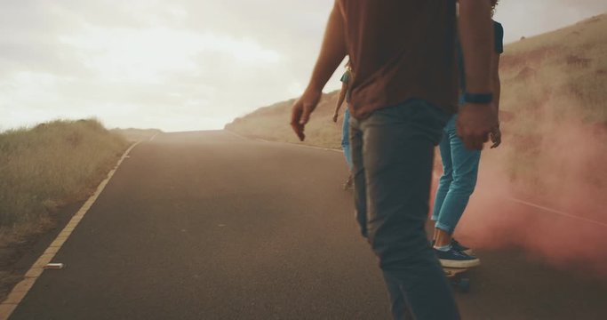 Three young adventurous friends skateboarding together with colorful pink smoke trails, stylish millennials riding skateboards with funky fun pink smoke