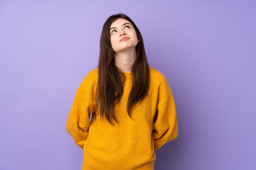 Fototapeta premium Young Ukrainian teenager girl over isolated purple background and looking up