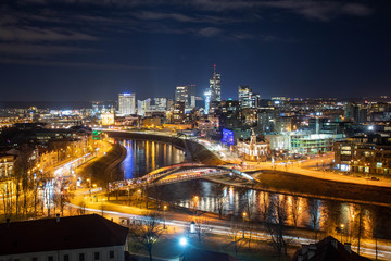 Vilnius, Lithuania, Europe, night scenic aerial panorama of modern business financial district architecture buildings with Neris river and bridge 