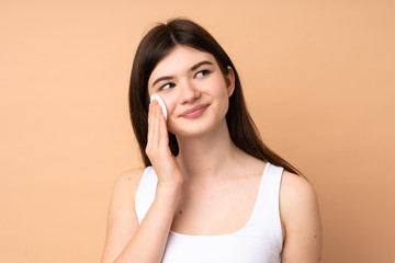 Young Ukrainian teenager girl over isolated background with cotton pad for removing makeup from her face