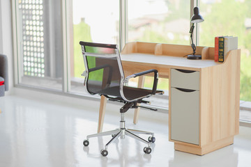 Workplace with table, office chair and lamp in living room,office corner with garden view