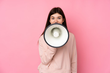 Young Ukrainian teenager girl over isolated pink background shouting through a megaphone