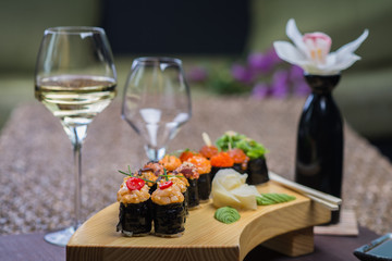 Set of several different rolls on a wooden stand on a table in a Japanese restaurant. Japanese traditional sushi and rolls.