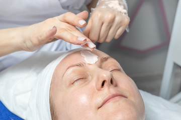 Close-up beautician doctor hands making anti-age procedures, facial and head massage for mid-aged female client at beauty clinic. Cosmetologist doing skincare treatment .Health care therapy