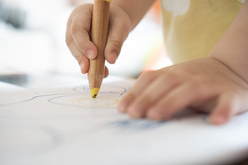 Close up hand of 2year kid use color pencil draw line on paper. Concept of art for children...