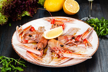 Seafood. Langoustine, scampi or Norway lobster with lemon on white plate.