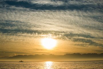 Naklejka premium Silhouette of Speed boat in the ocean at sunset. oating at sunset in Atlantic ocean, South Africa