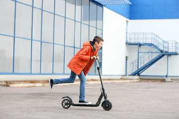 Teenage boy riding kick scooter outdoors © Pixel-Shot