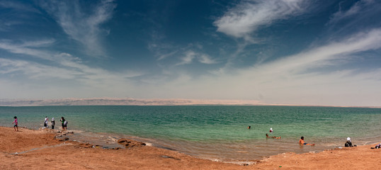 Fototapeta na wymiar Some bathers float on the waters of the Dead Sea in Jordan.