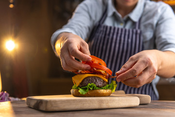 Close up of a female chef, preparing a tasty, fresh, delicious hamburger in a restaurant or pub