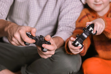 Father and his little daughter playing video games at home in evening, closeup