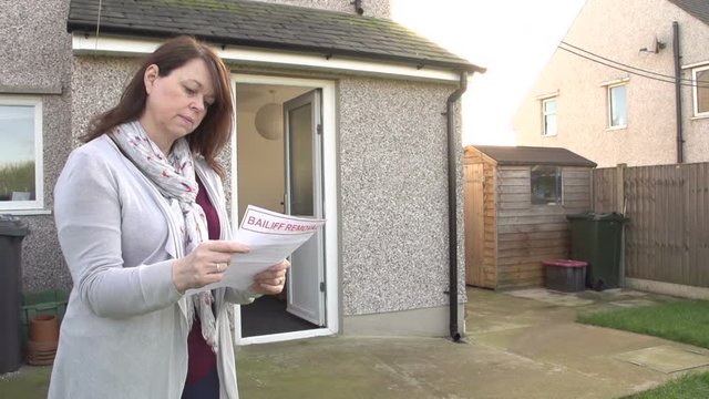 Woman reading letter from Bailiff as Debt Collector takes her TV from her house. Repossession. Repo Man. Stock Video Clip Footage. Slow Motion