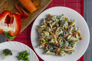 pasta with vegetables and cheese on a white plate red background home cooking
