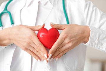 Female cardiologist with red heart, closeup