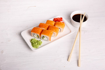 rolls with salmon, cream cheese and avacado, restaurant menu on a light wooden background