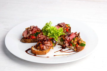 bruschetta with grilled meat and vegetables menu for the restaurant on a light wooden background
