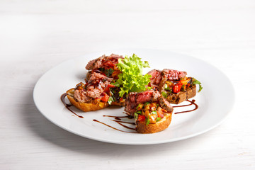 bruschetta with grilled meat and vegetables menu for the restaurant on a light wooden background