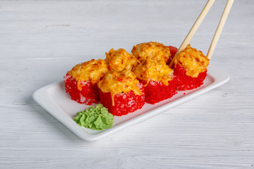 Close-up of hot sushi rolls with caviar and cheese served on a white background.