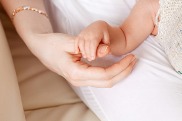 Obraz na płótnie Canvas Newborn children's hand in mother hand. Mom and her Child. Happy Family concept. Beautiful conceptual image of Maternity