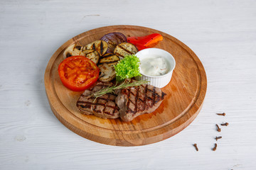 Grilled beef steak served on a wooden Board with fried vegetables