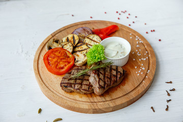 Grilled beef steak served on a wooden Board with fried vegetables