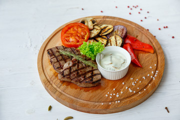 Grilled beef steak served on a wooden Board with fried vegetables